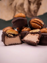 Chocolate-covered treats with pecans on a white surface