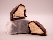 Chocolate-dipped confection with a creamy center on a light pink background