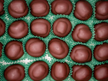 Close-up of chocolate candies in green wrappers on a green grid.