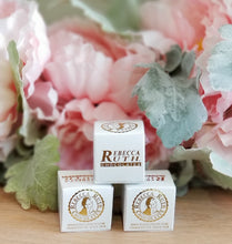 Boxes of individually boxed bourbon balls from Rebecca Ruth Chocolate, presented in front of a floral backdrop.